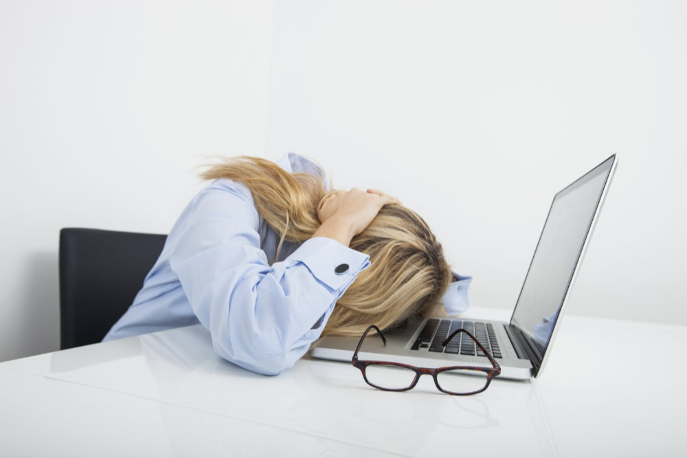 linkfool - Tired businesswoman resting head on laptop in office